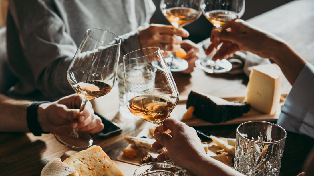 Friends clinking wine glasses over a cheese board while learning about wine tasting basics